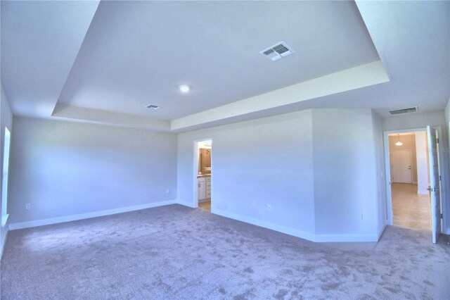 carpeted empty room with a raised ceiling