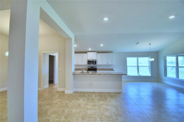 kitchen featuring light tile patterned flooring, sink, light stone counters, and white cabinetry