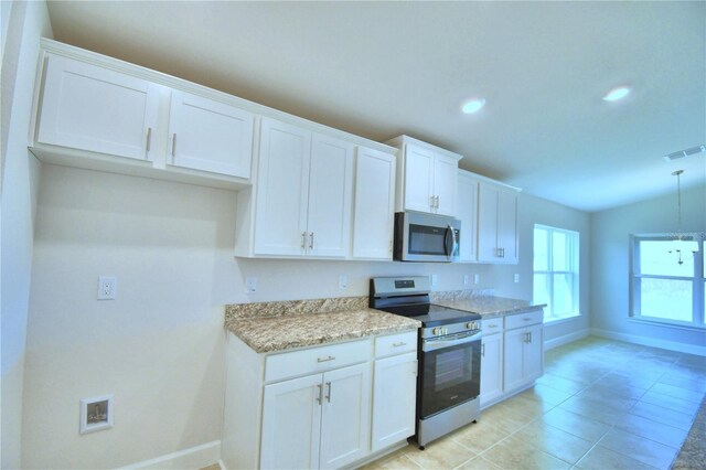 kitchen featuring white cabinetry, light stone counters, vaulted ceiling, appliances with stainless steel finishes, and light tile patterned floors