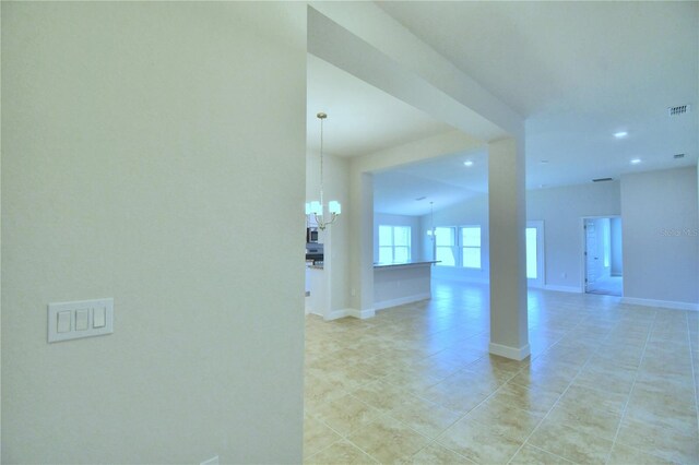 tiled empty room with an inviting chandelier