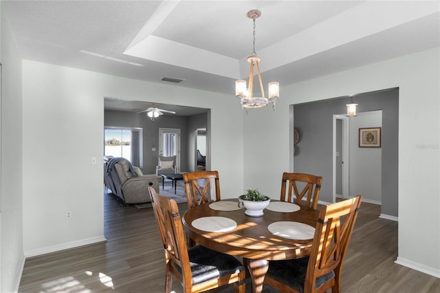 dining space with ceiling fan with notable chandelier and dark hardwood / wood-style flooring