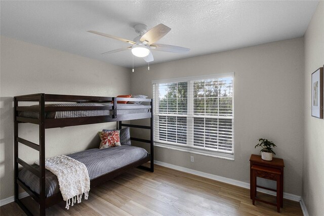 bedroom with ceiling fan, light wood-type flooring, and a textured ceiling