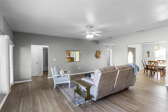 living room featuring hardwood / wood-style flooring and ceiling fan with notable chandelier