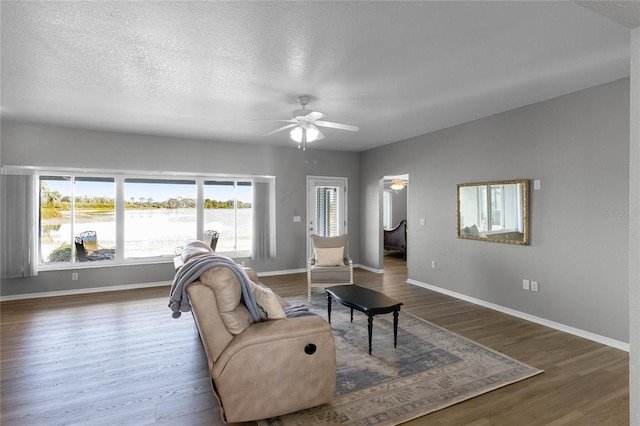 living room featuring ceiling fan, dark hardwood / wood-style flooring, and a textured ceiling