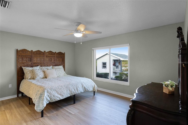 bedroom with ceiling fan, a textured ceiling, and light wood-type flooring