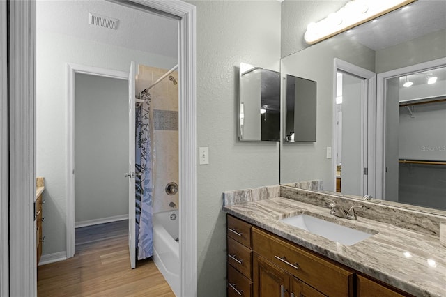 bathroom featuring vanity, shower / bath combination with curtain, a textured ceiling, and hardwood / wood-style flooring