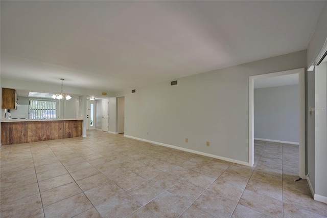 unfurnished living room with tile patterned flooring and a notable chandelier