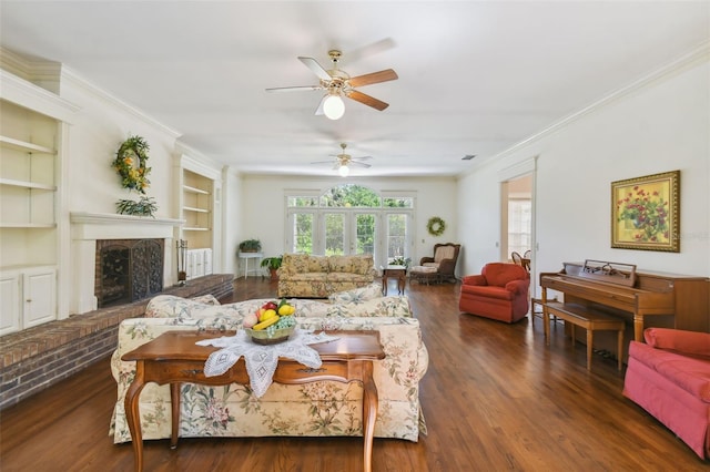 living room with built in features, dark hardwood / wood-style flooring, ceiling fan, a brick fireplace, and ornamental molding