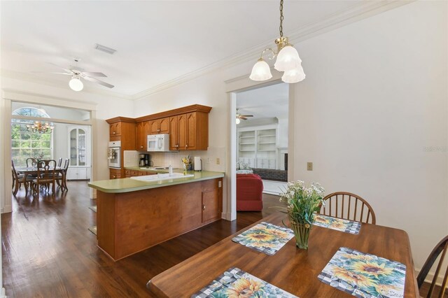 kitchen with ceiling fan with notable chandelier, dark hardwood / wood-style flooring, white appliances, and ornamental molding