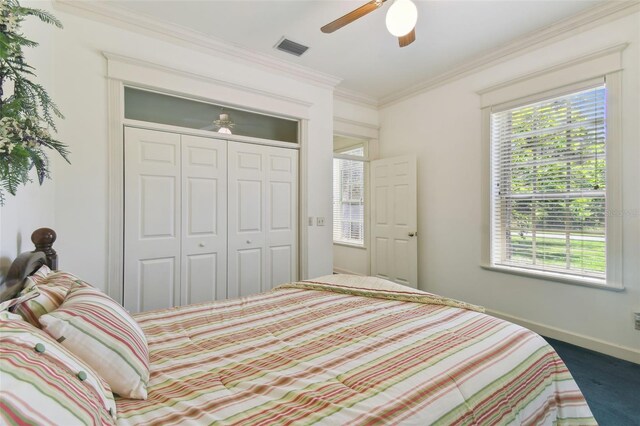 carpeted bedroom featuring multiple windows, ceiling fan, and a closet