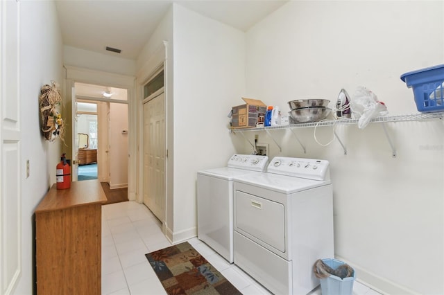 clothes washing area featuring washer and clothes dryer and light tile patterned floors