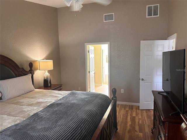 bedroom with a towering ceiling, dark hardwood / wood-style flooring, and ceiling fan