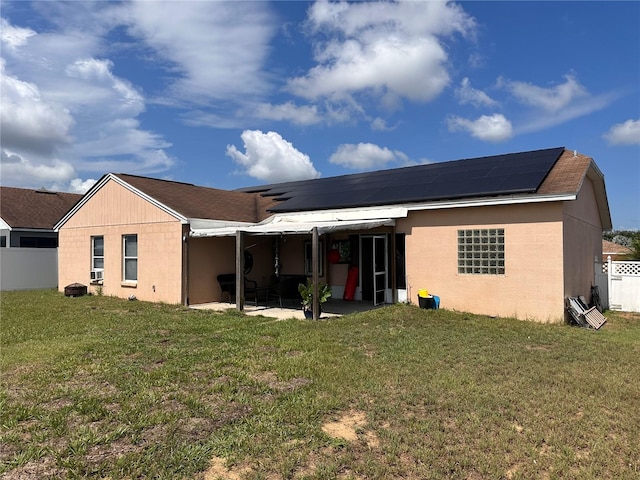 back of house with a patio, a yard, and solar panels