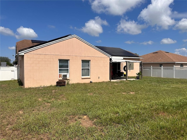 back of house with a lawn and solar panels