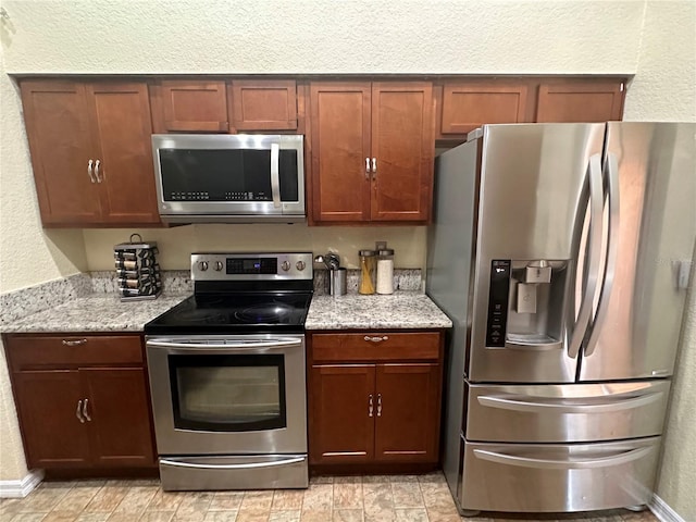 kitchen featuring light tile patterned flooring, appliances with stainless steel finishes, and light stone counters