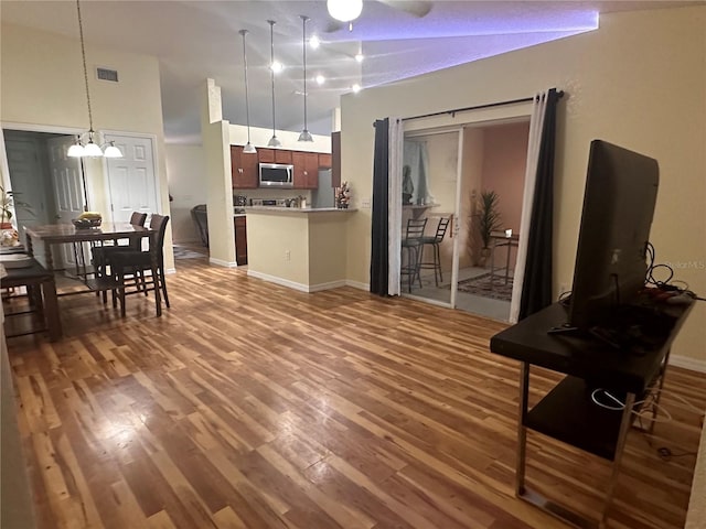 living room with ceiling fan with notable chandelier, wood-type flooring, and a towering ceiling