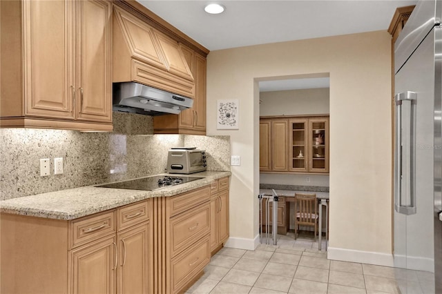 kitchen with light tile patterned floors, light stone countertops, black electric cooktop, decorative backsplash, and high quality fridge