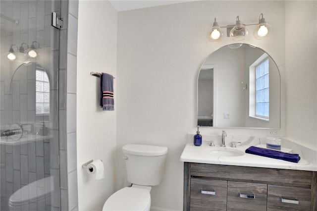 bathroom with toilet, an enclosed shower, and vanity