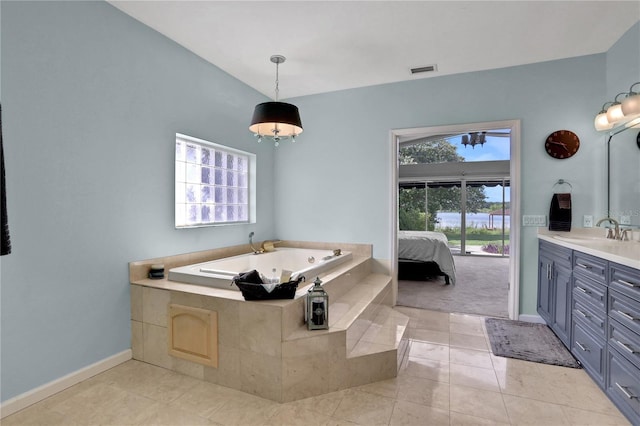 bathroom with tiled tub, tile patterned floors, and vanity