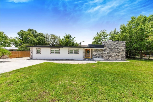 view of front of property with a front lawn, fence, and stone siding