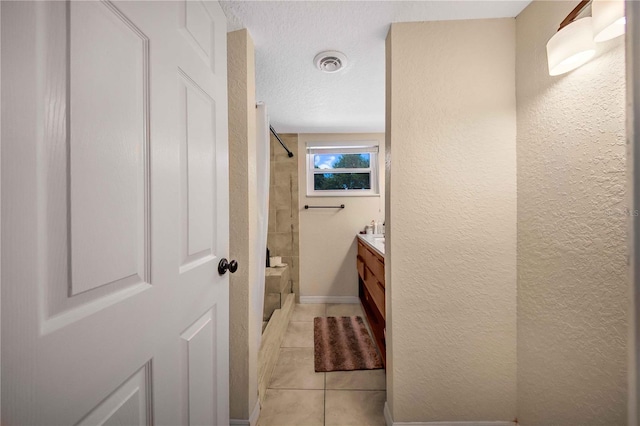 bathroom featuring tile patterned flooring, tiled shower / bath, vanity, and a textured ceiling