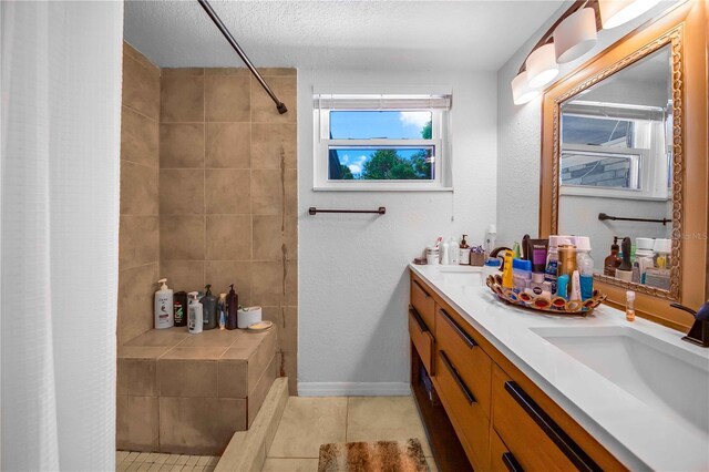 bathroom with tile patterned floors, a textured ceiling, and double vanity