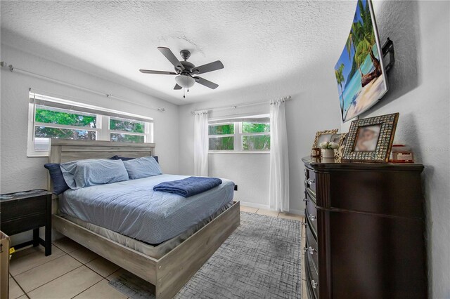 bedroom featuring tile patterned flooring, ceiling fan, and a textured ceiling