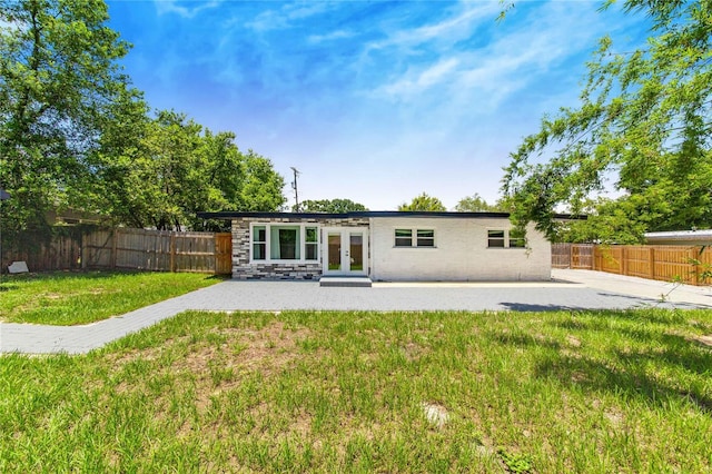 rear view of house featuring a patio area, a lawn, and french doors