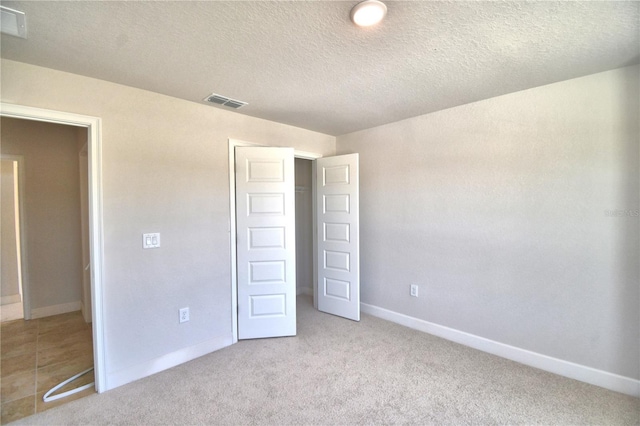 unfurnished bedroom with a textured ceiling and light carpet