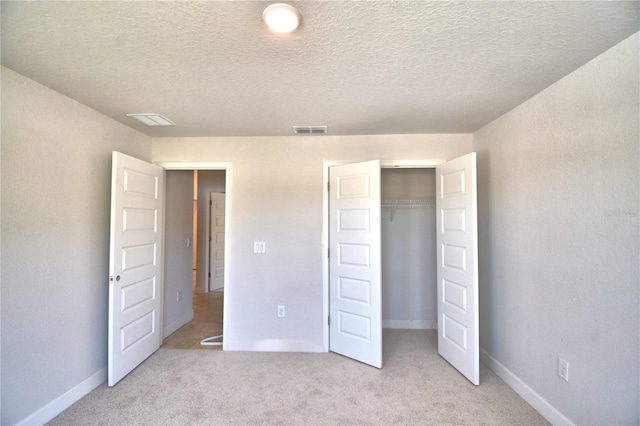 unfurnished bedroom with light carpet, a closet, and a textured ceiling