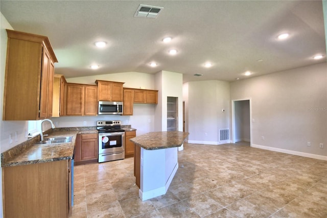 kitchen featuring a center island, sink, stainless steel appliances, dark stone countertops, and lofted ceiling