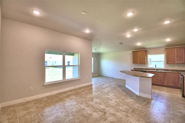 kitchen featuring a kitchen island, a wealth of natural light, and dark stone counters