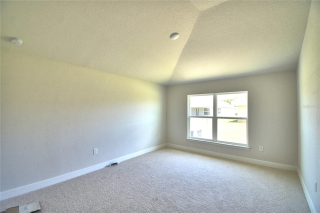 spare room featuring light carpet and lofted ceiling