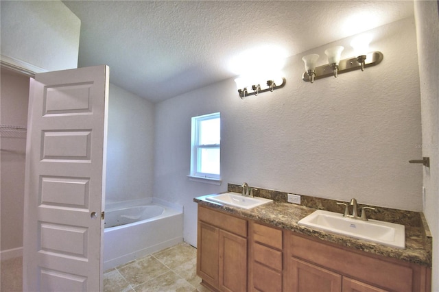 bathroom featuring a tub, vanity, and a textured ceiling