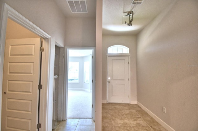 hall featuring light tile patterned floors and a textured ceiling