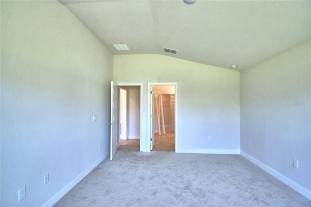 unfurnished bedroom with carpet, a walk in closet, a closet, and lofted ceiling