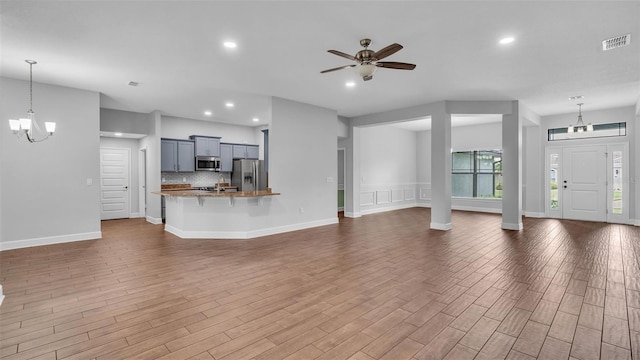 unfurnished living room featuring ceiling fan with notable chandelier