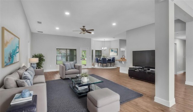 living room featuring ceiling fan with notable chandelier and light hardwood / wood-style floors