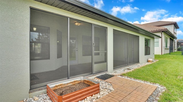 property entrance featuring a yard, a tile roof, fence, and stucco siding