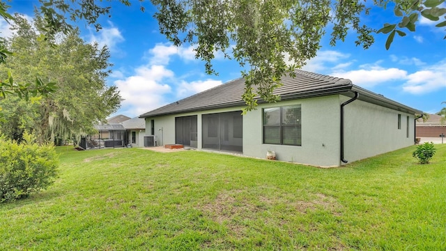 rear view of property with a sunroom, a lawn, and stucco siding