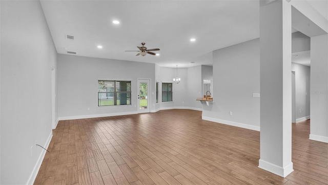 unfurnished living room featuring visible vents, wood finished floors, and ceiling fan with notable chandelier