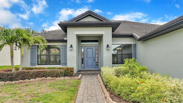 property entrance with stucco siding and a tiled roof