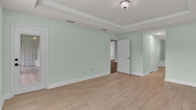 empty room with crown molding, light hardwood / wood-style flooring, and a raised ceiling