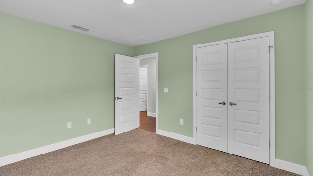 unfurnished bedroom with carpet, a closet, visible vents, and baseboards