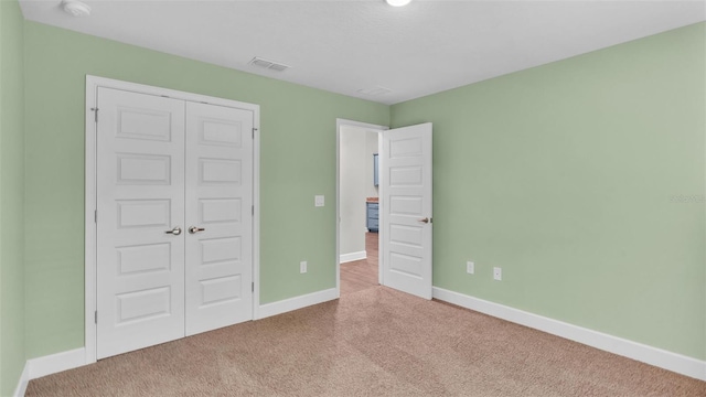 unfurnished bedroom with a closet and light carpet