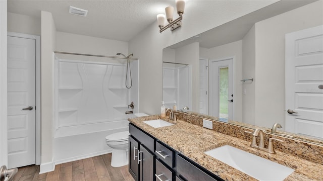 full bathroom featuring toilet, vanity, shower / washtub combination, hardwood / wood-style flooring, and a textured ceiling