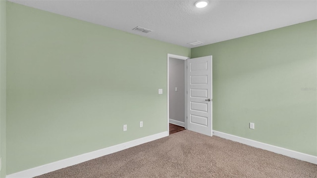 carpeted empty room featuring a textured ceiling