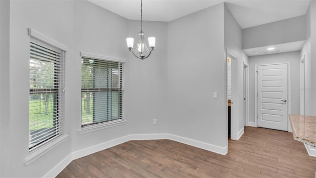 spare room featuring light hardwood / wood-style floors and an inviting chandelier