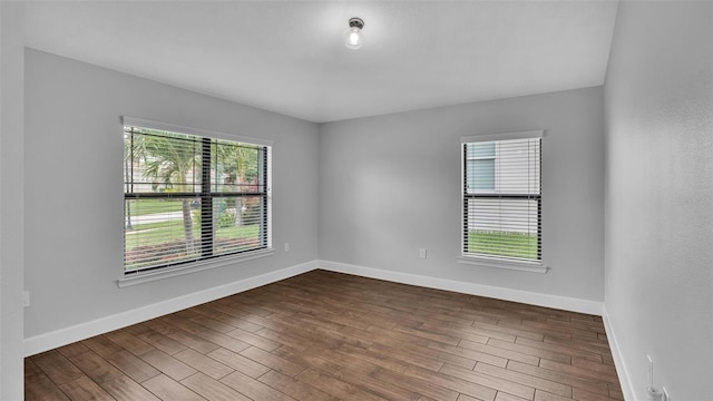 unfurnished room featuring dark wood-style flooring and baseboards