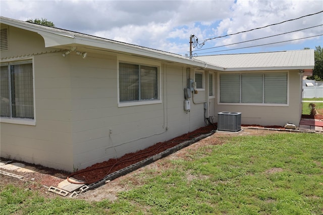 view of side of property with cooling unit and a lawn